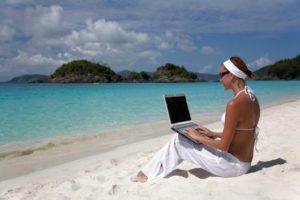 woman working on a laptop at a perfect beach in the caribbean